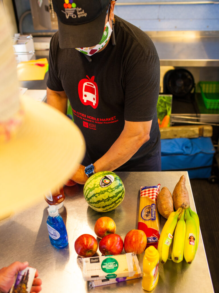 bird's-eye view of a checkout counter featuring bananas, apples, butter, watermelon, cheese, and yams