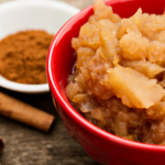 cinnamon sticks, ground cinnamon, and some mashed apples in a red bowl