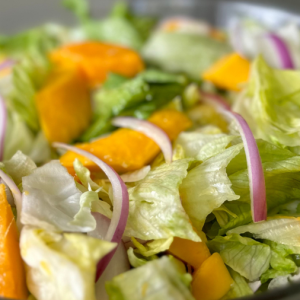 salad with chopped lettuce, yellow mango, and red onion slices