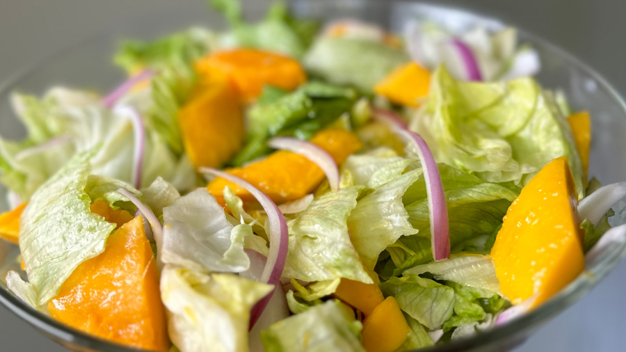 salad with chopped lettuce, yellow mango, and red onion slices