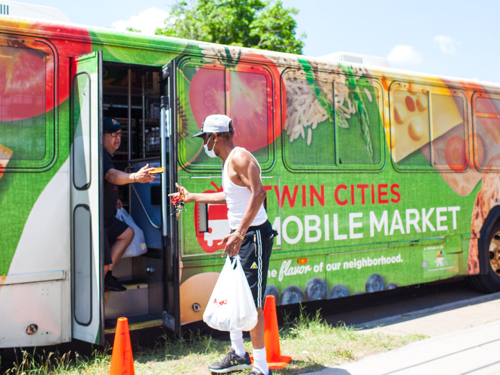 An interaction between two people at the bus door of the Twin Cities Mobile Market.