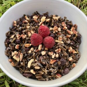 a bowl of wild rice with blueberries, topped with pecans and raspberries