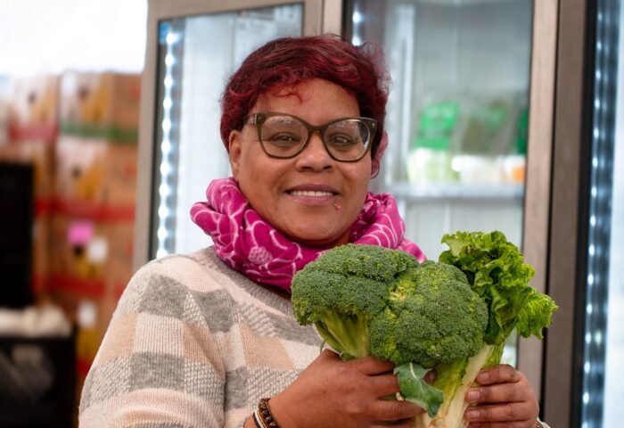 Participant shopping at food shelf and holding broccoli.