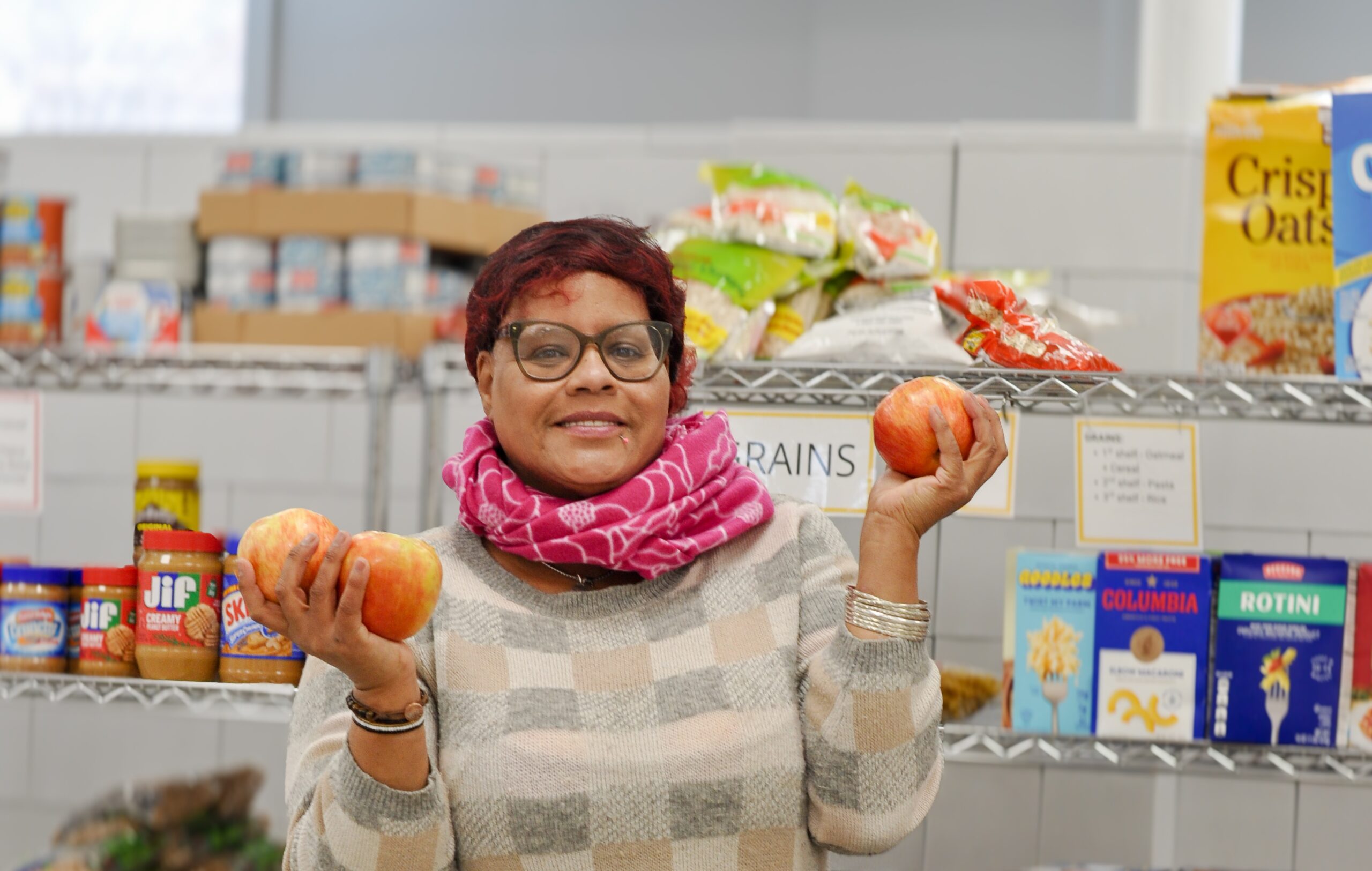 Food shelf participant holding apples.