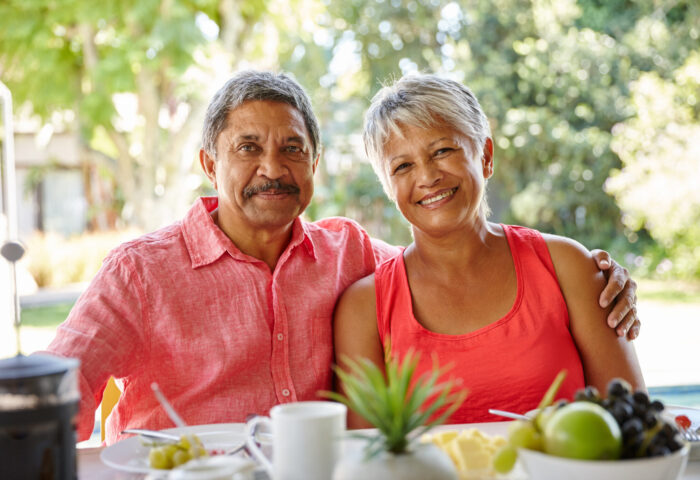 Two happy people sit at a table smiling with food and coffee