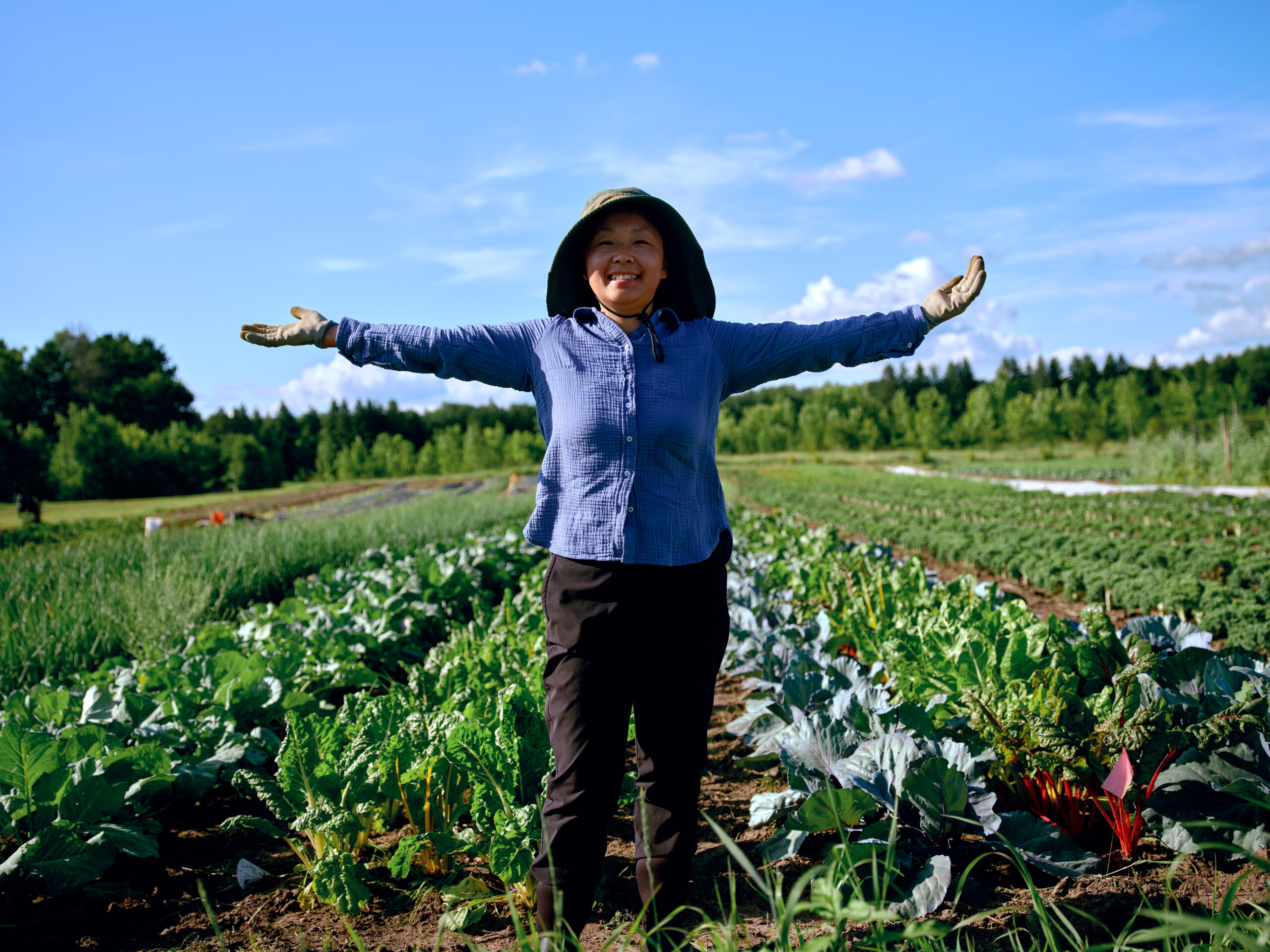 a farmer gestures with wide arms to her plot at Big River Farms