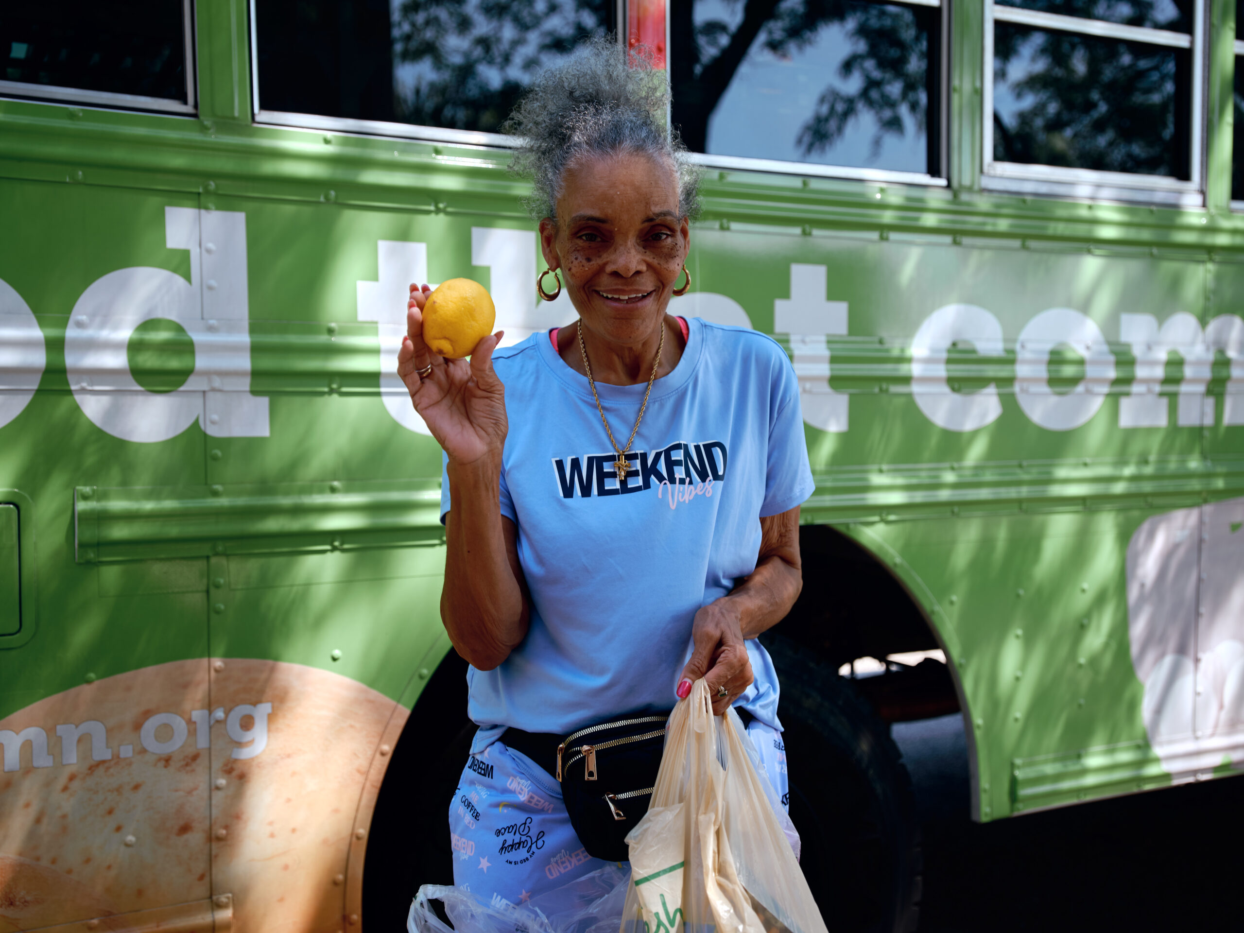 A shopper holds up a lemon in front of the Twin Cities Mobile Market bus
